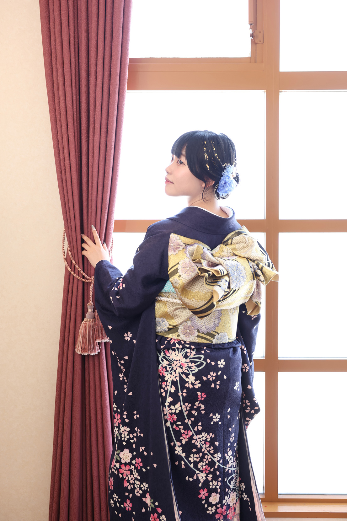 紺色の振袖の窓辺での後ろ姿